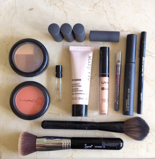 Os produtos acima são: batons, bronzer, blush, mini perfume, base, corretivo, lápis de olho, rímel e pinceis. 